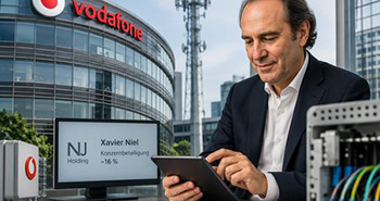 ein Mann schaut auf sein Tablet und im Hintergrund ist ein Geb&auml;ude mit Vodafone Schriftzug an der Fassade.